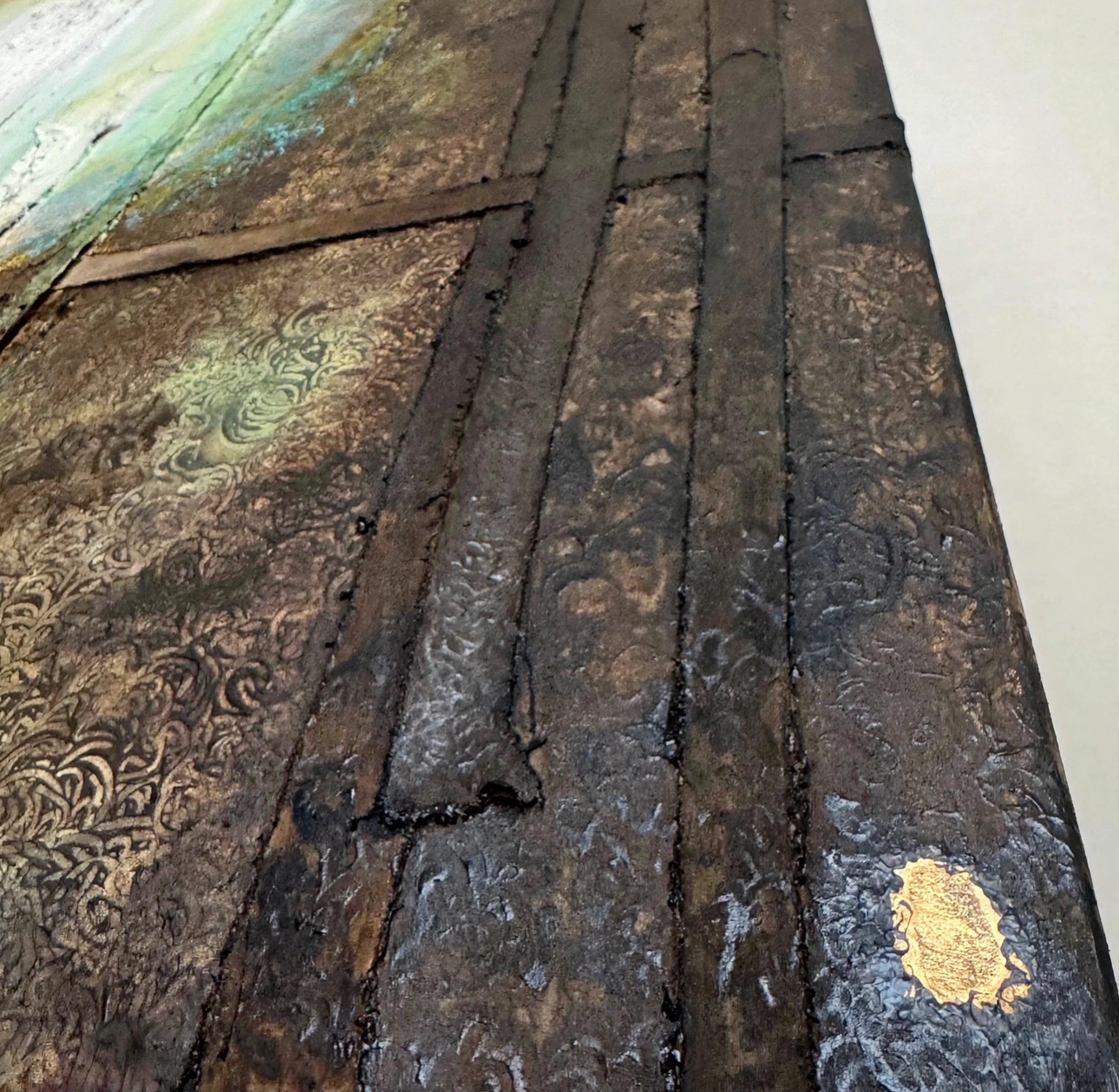Detail van een kunstwerk van ANDA met gelaagde donkere texturen, ornamenten, groen en een goudkleurig accent